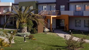 A modern multi-story residential building with a central staircase, a well-maintained lawn, and a palm tree. - Alto Miramar Resort & Spa (Miramar)