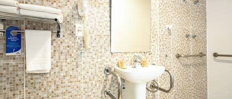 A bathroom with a tiled mosaic backsplash, a white sink with a handheld showerhead, a towel rack, and a mirror.