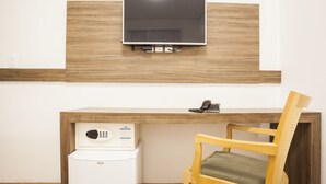 A room with a wooden desk, a chair, a flat-screen TV mounted on the wall, and a small white appliance. - Travel Inn Express Hotels Brás (São Paulo)