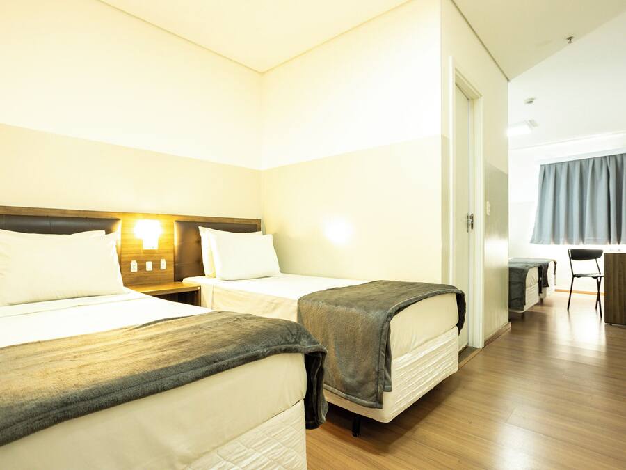 A hotel room with two beds, a desk, and a chair.