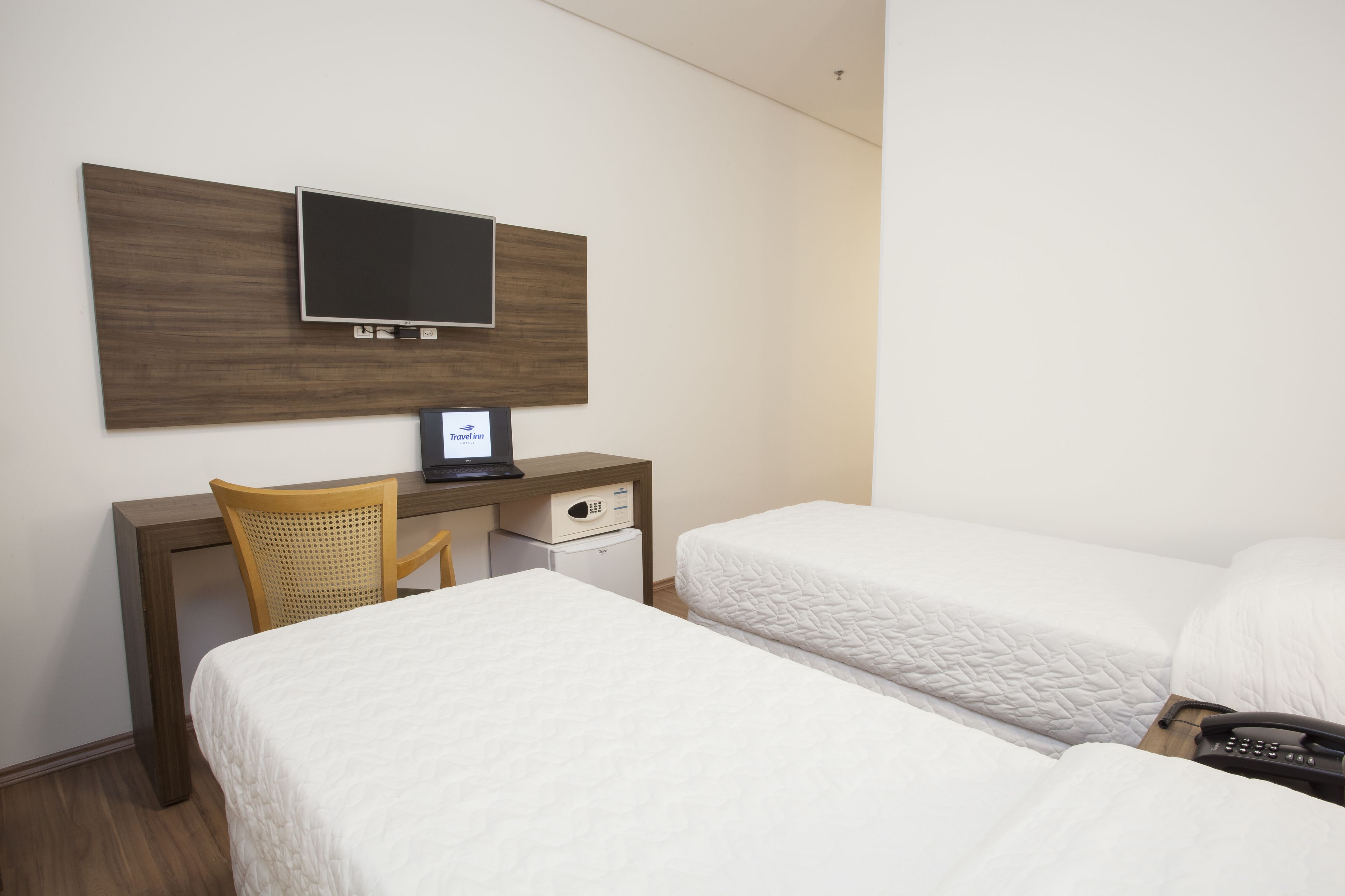 Une chambre d’hôtel comprenant un lit, un bureau avec une chaise, une télévision et un minibar.