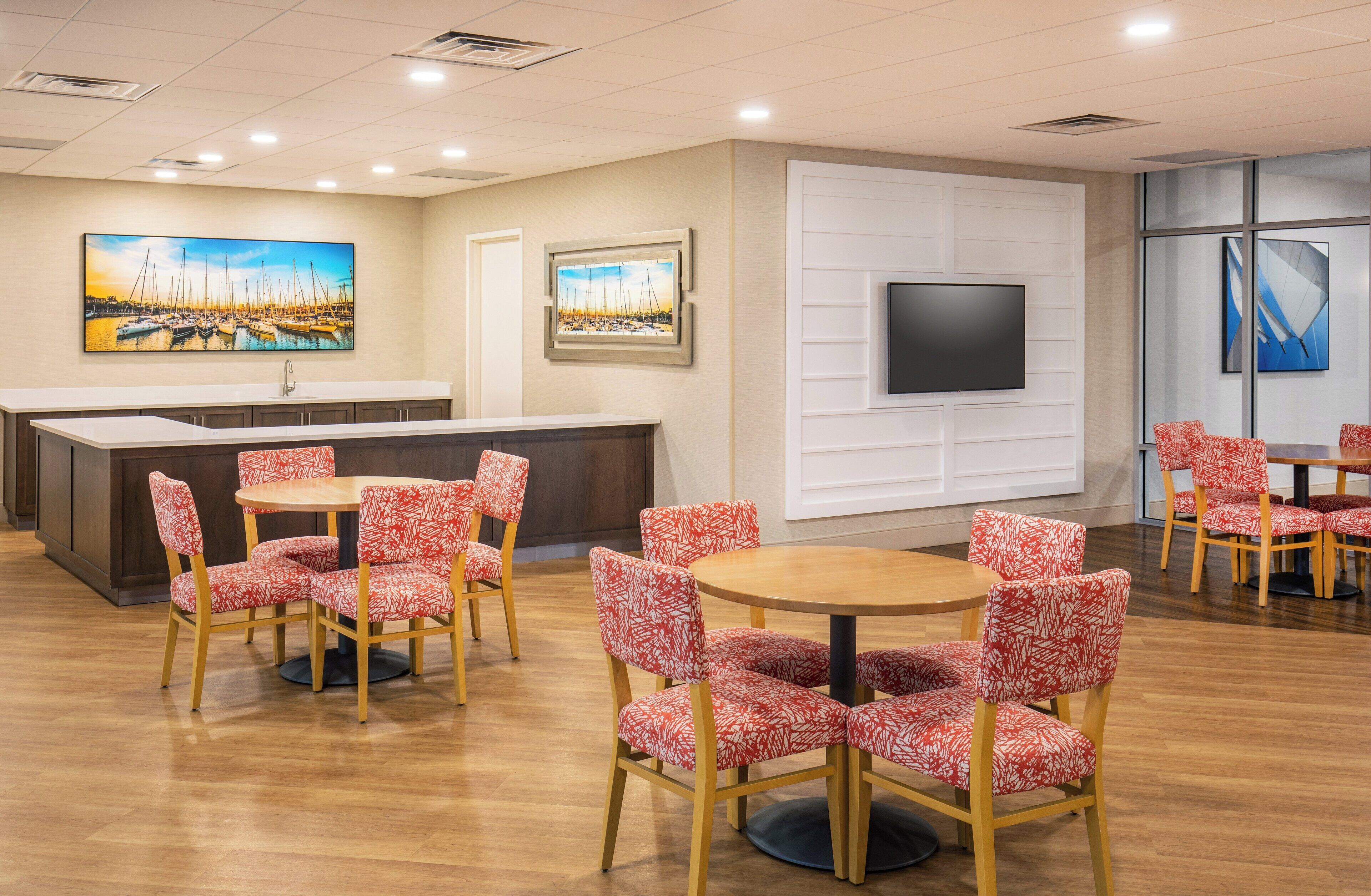 A hotel lobby with a reception desk, a flat-screen TV, and multiple seating areas with patterned chairs.