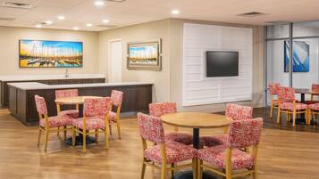 A hotel lobby with a reception desk, a flat-screen TV, and multiple seating areas with patterned chairs.