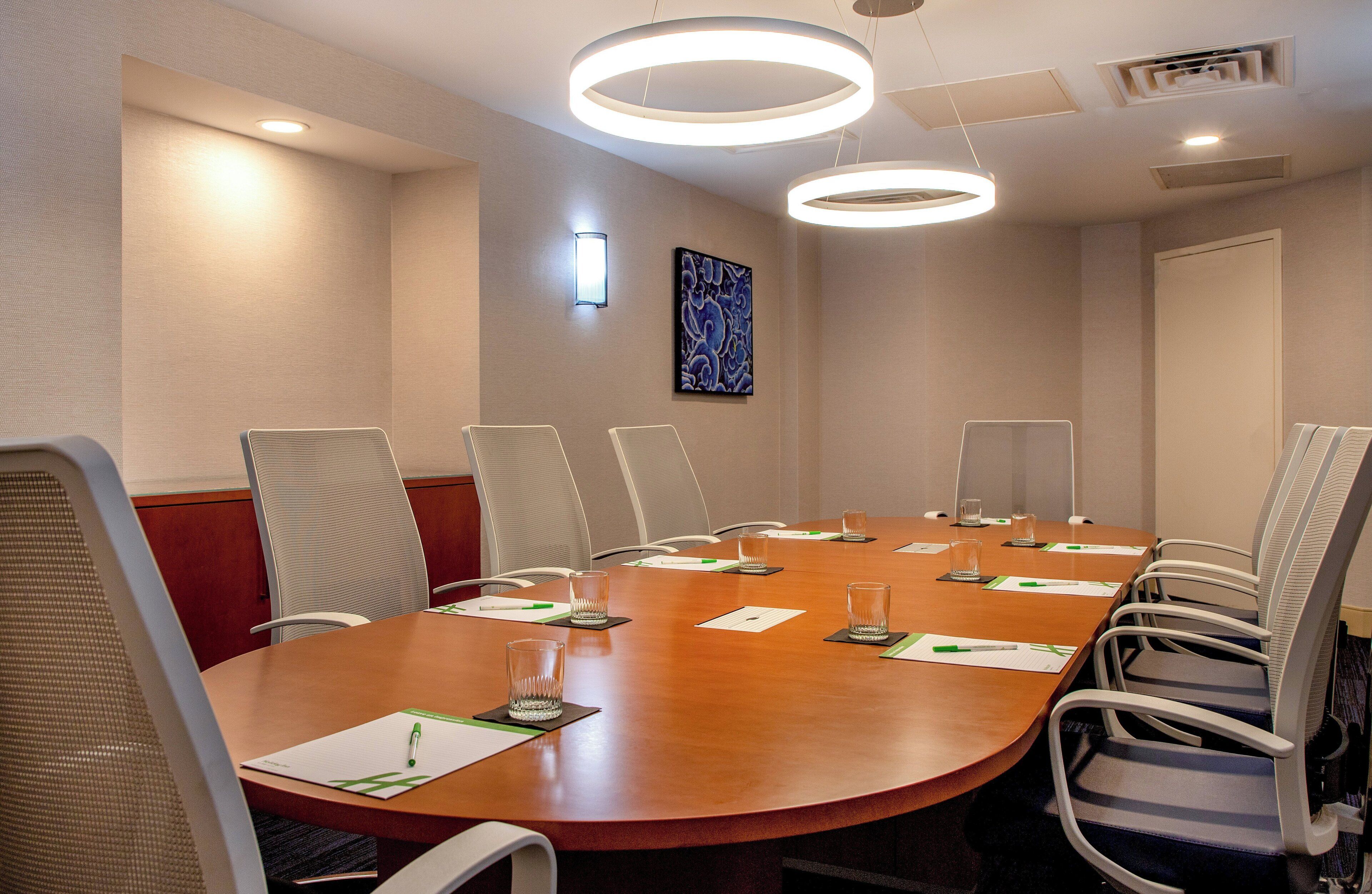 A conference room with a round table, chairs, and overhead lighting.