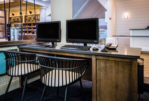 Een bar met twee schermen, een toetsenbord, een telefoon en twee stoelen.