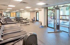 Un gimnasio con cintas de correr, mancuernas y equipo de ejercicio.