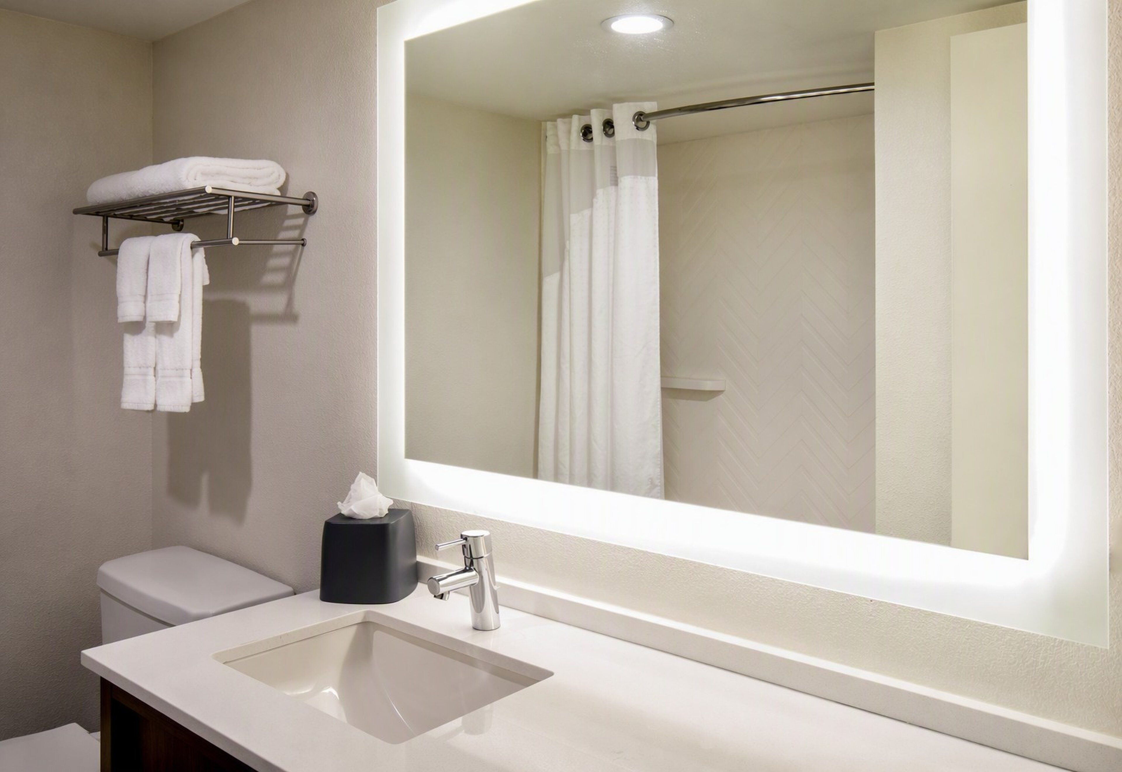 A bathroom with a sink, mirror, towel rack, and a shower curtain.