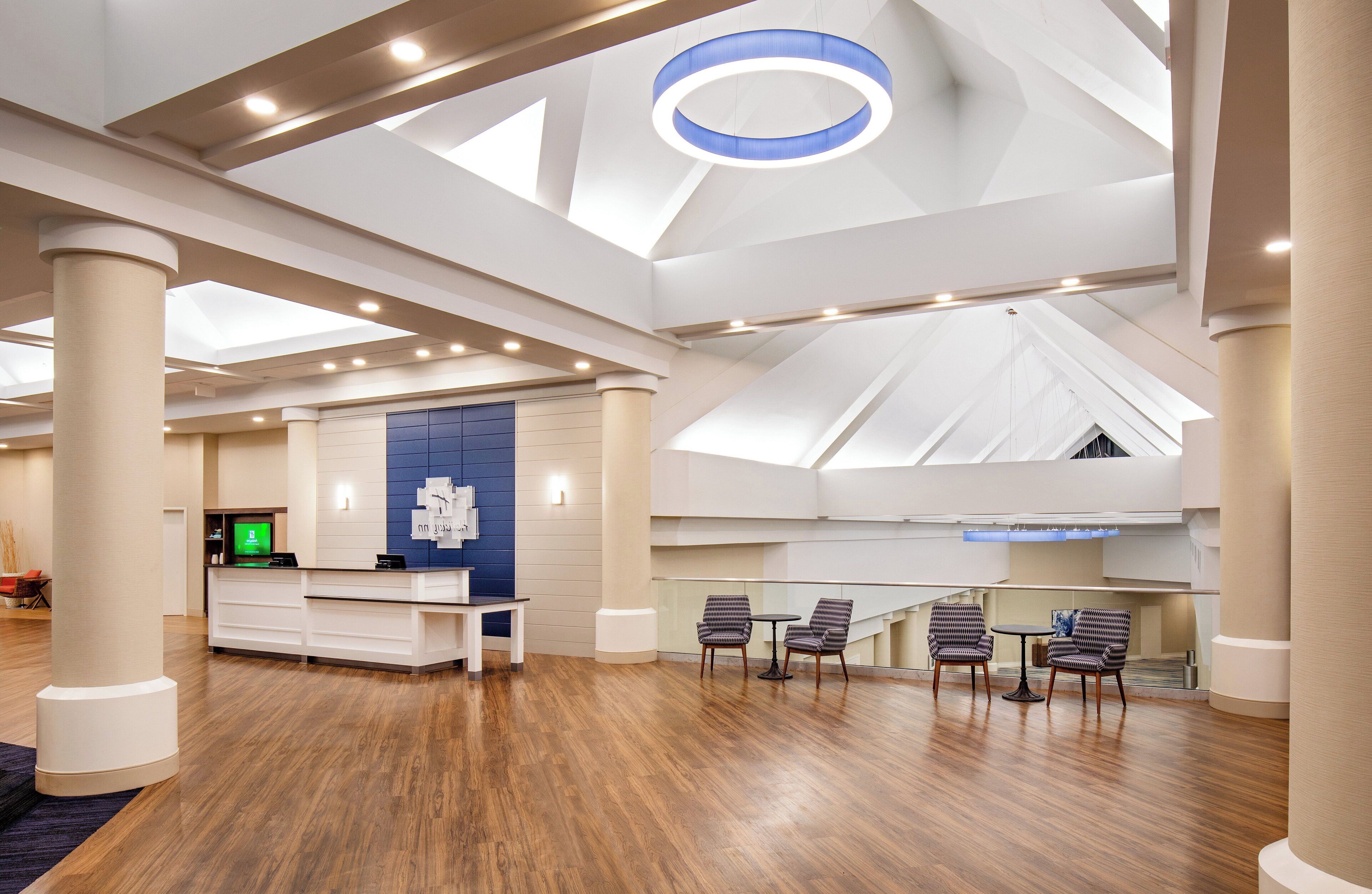 A spacious lobby with a reception desk, seating area, and a high ceiling with skylights.