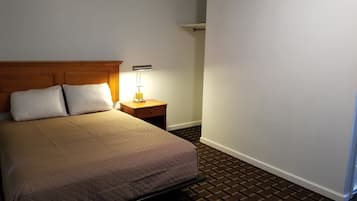 Habitación de hotel con una cama, dos almohadas, una mesita de noche con lámpara y suelo con estampado de ladrillo.