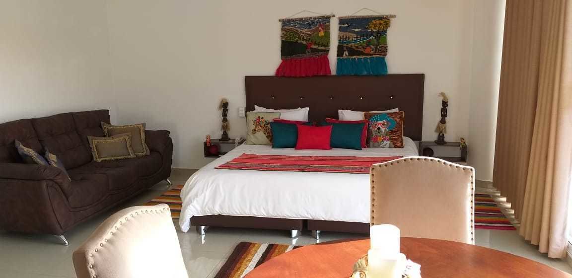 A bedroom with a bed, a sofa, a chair, and a table.