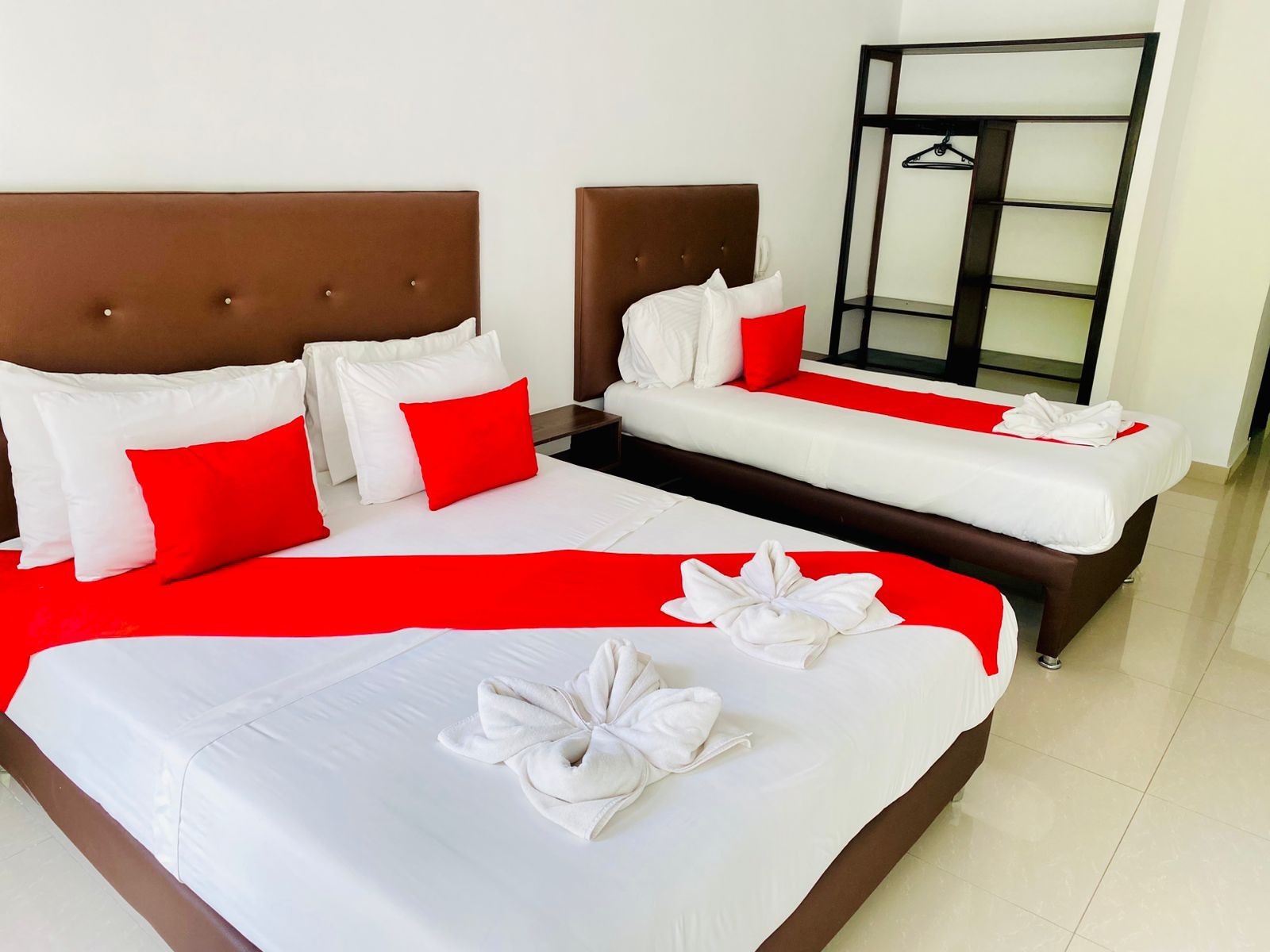 A hotel room with two beds, a red and white color scheme, and a neatly made bed with a towel.