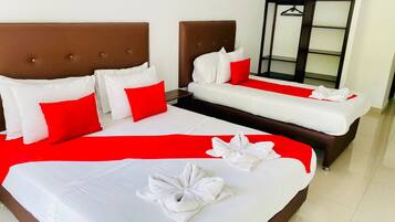 A hotel room with two beds, a red and white color scheme, and a neatly made bed with a towel.