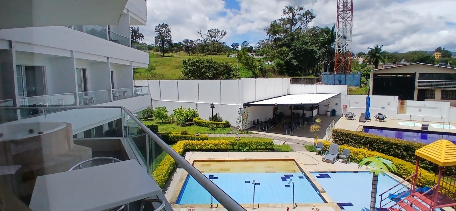 A hotel with a pool area, outdoor seating, and a view of the surrounding landscape.