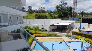 A hotel with a pool area, outdoor seating, and a view of the surrounding landscape.