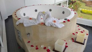 Un bain à remous décoré de pétales de rose et de serviettes disposées en forme de cœur.