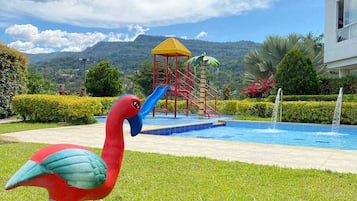 Una piscina al aire libre, sombrillas, sillones reclinables de piscina
