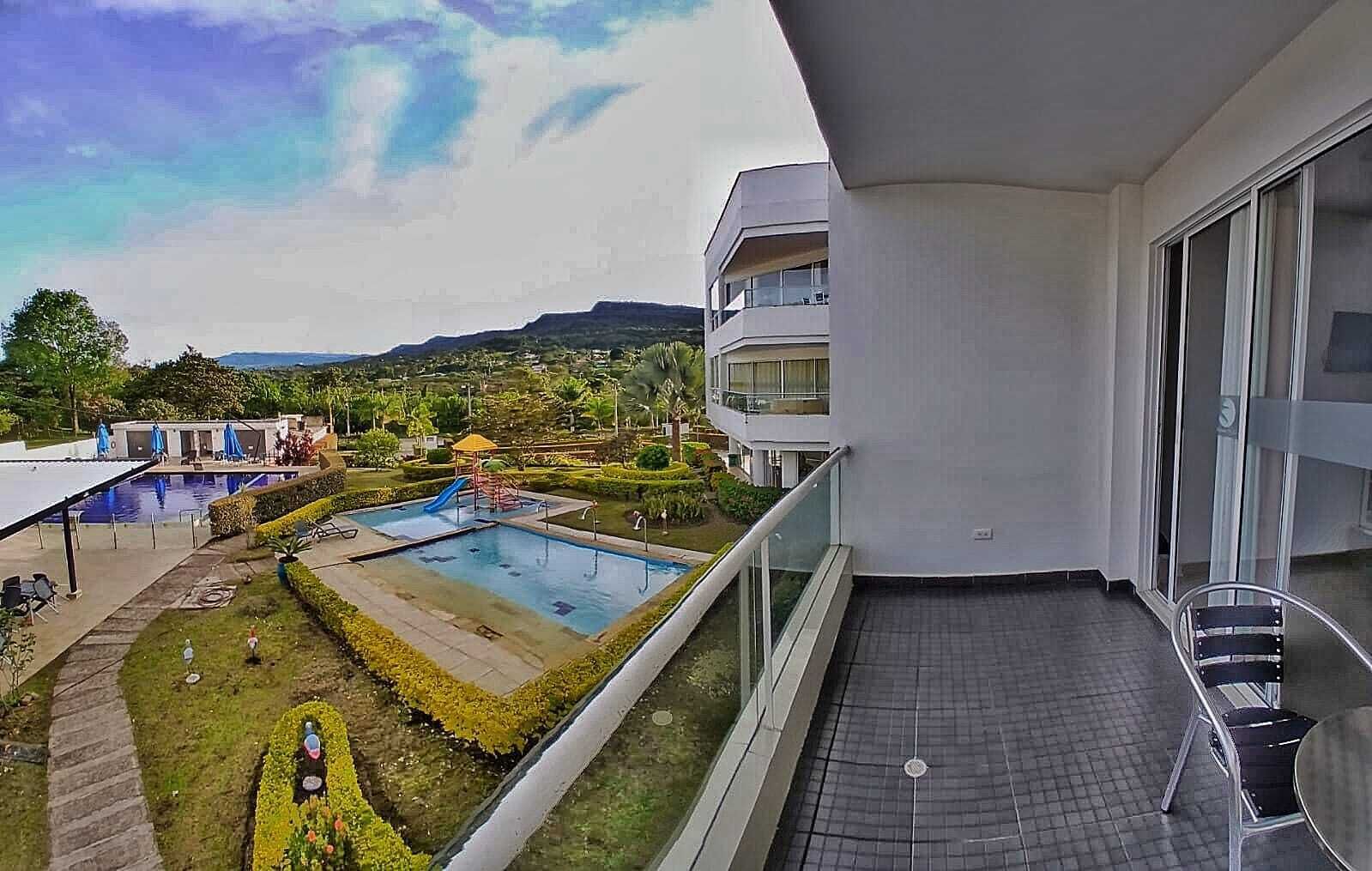Un balcon avec vue sur une piscine et un jardin aménagé.