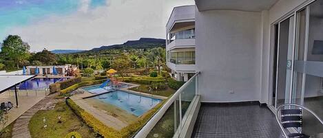 Un balcon avec vue sur une piscine et un jardin aménagé.