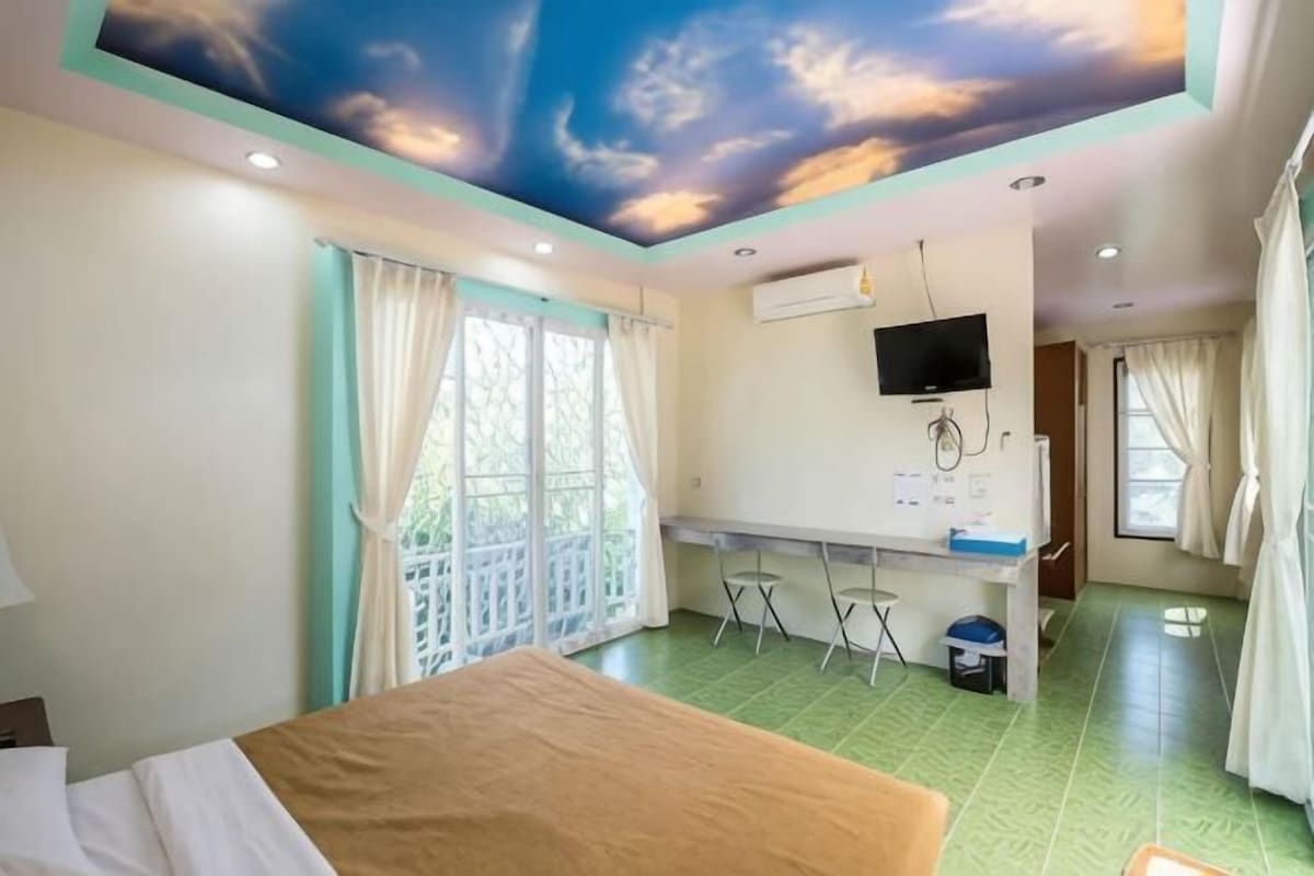A room with a bed, a desk, and a ceiling mural.