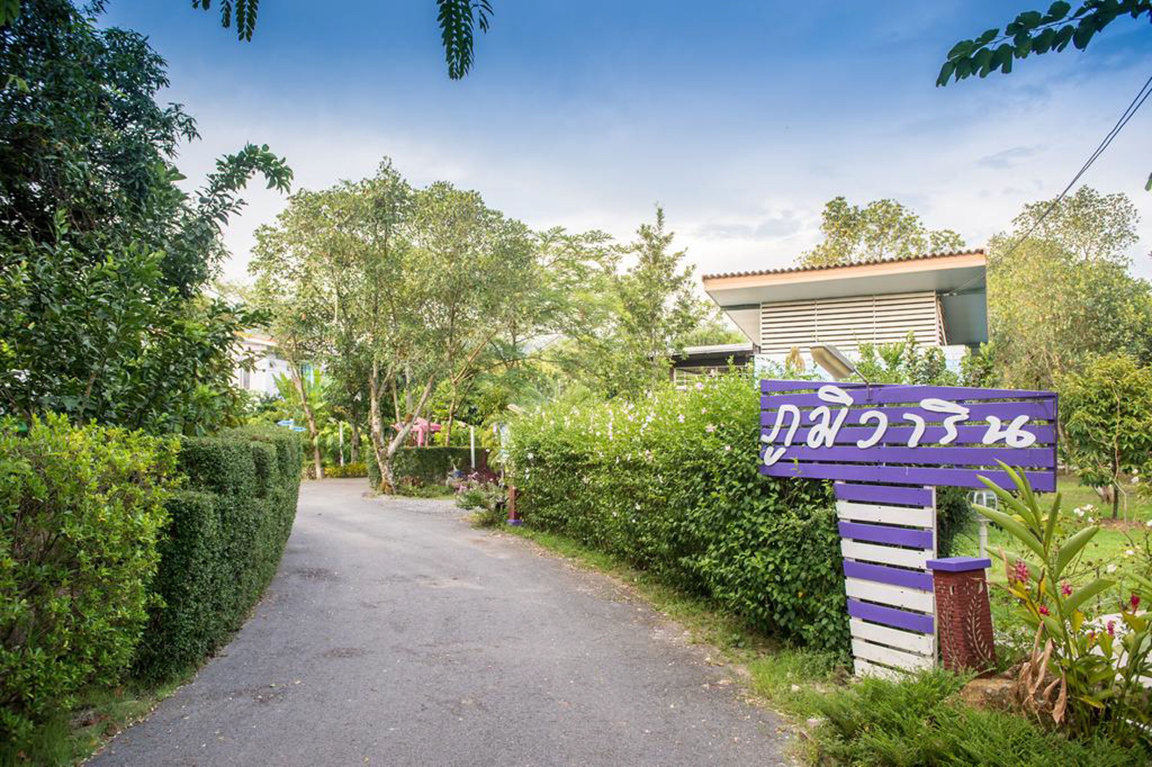 Un chemin menant à un bâtiment sur lequel est apposée une enseigne dans une langue étrangère.