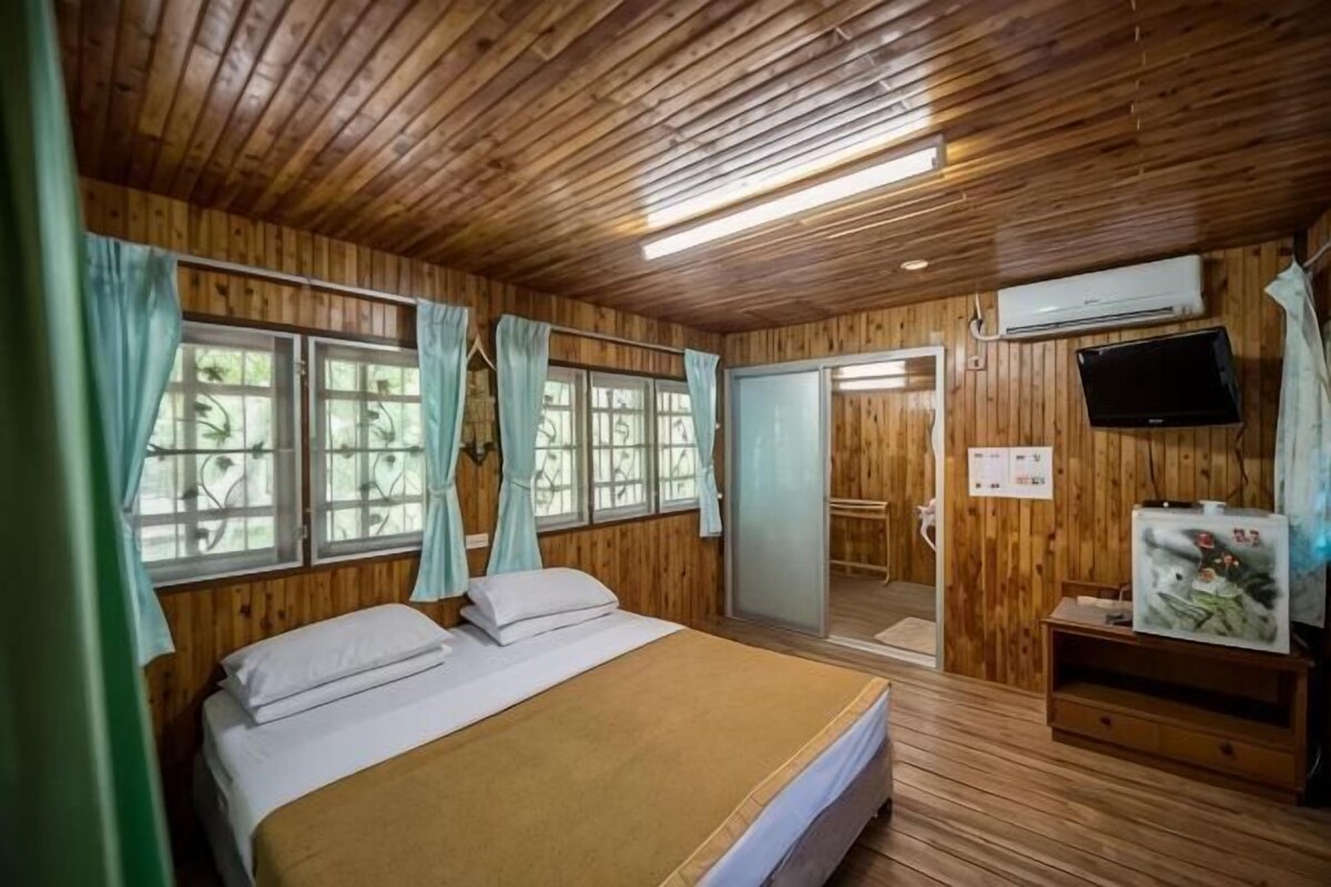 A wooden-paneled room with a bed, a television, and a sliding door.