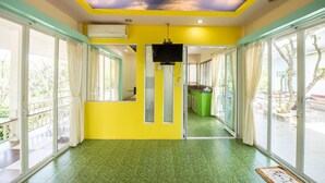 A room with a yellow and green color scheme, large windows, and a ceiling with a painted sky design. - Poomvarin Resort (Nakhon Nayok)