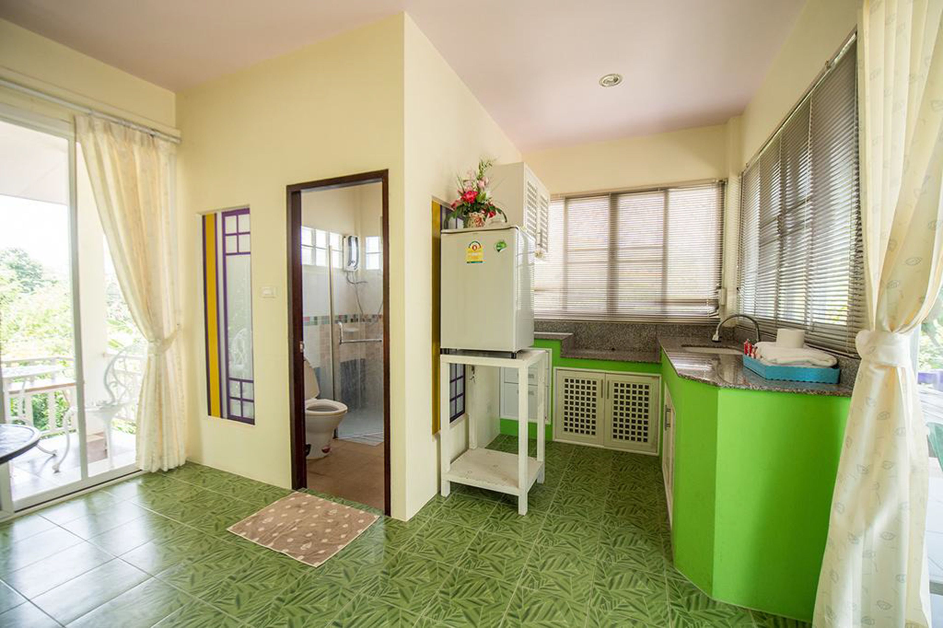 A compact kitchen with a green countertop, a refrigerator, and a sink.