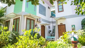 A two-story building with a green and white facade, multiple windows, and a small balcony. - Poomvarin Resort (Nakhon Nayok)