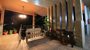 A covered outdoor area with a wooden deck, a bench, and a table. - Nava Resort (Pak Phli)