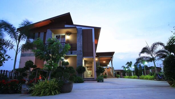 A modern two-story building with a covered entrance and a landscaped garden. - Nava Resort (Pak Phli)