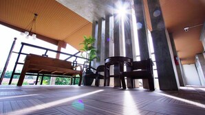 A spacious indoor area with a wooden ceiling, large windows, and a bench. - Nava Resort (Pak Phli)