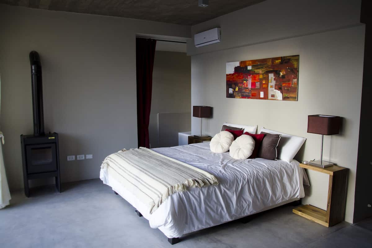 Une chambre à coucher moderne avec un grand lit, un radiateur portatif, un tableau au mur et deux lampes de chevet.