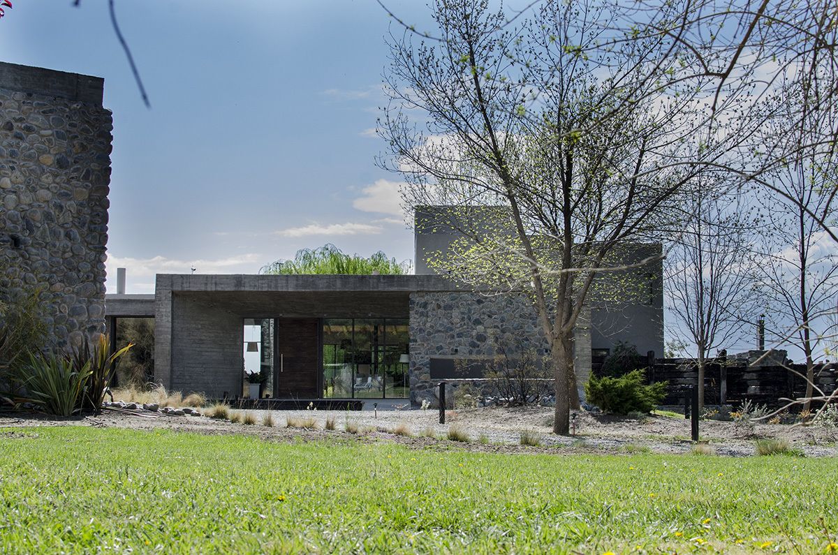 Een modern gebouw met een stenen gevel, grote glazen ramen en een verzorgd gazon.