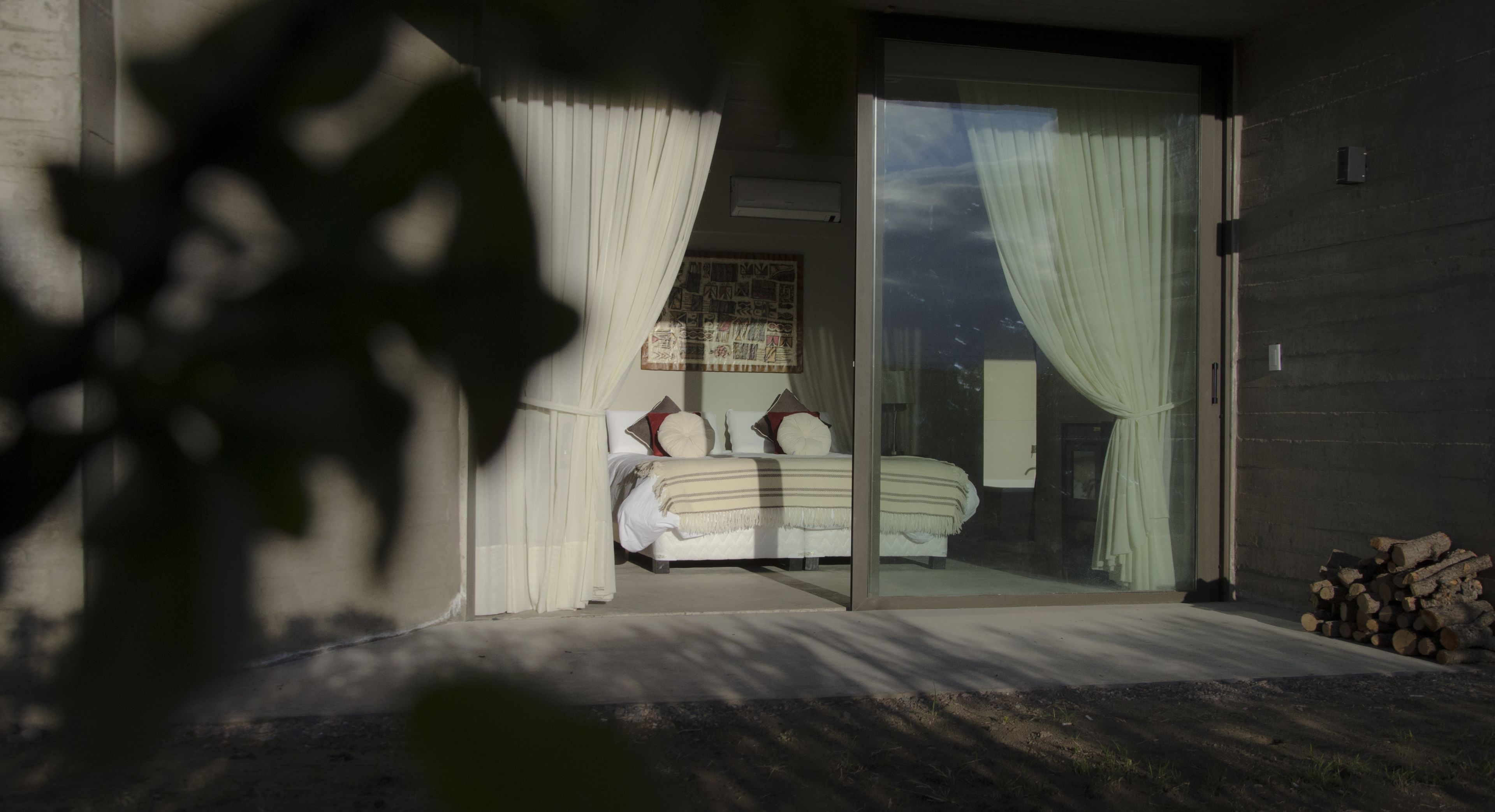 Un dormitori amb llit, cortines i vistes a través d'una porta de vidre.