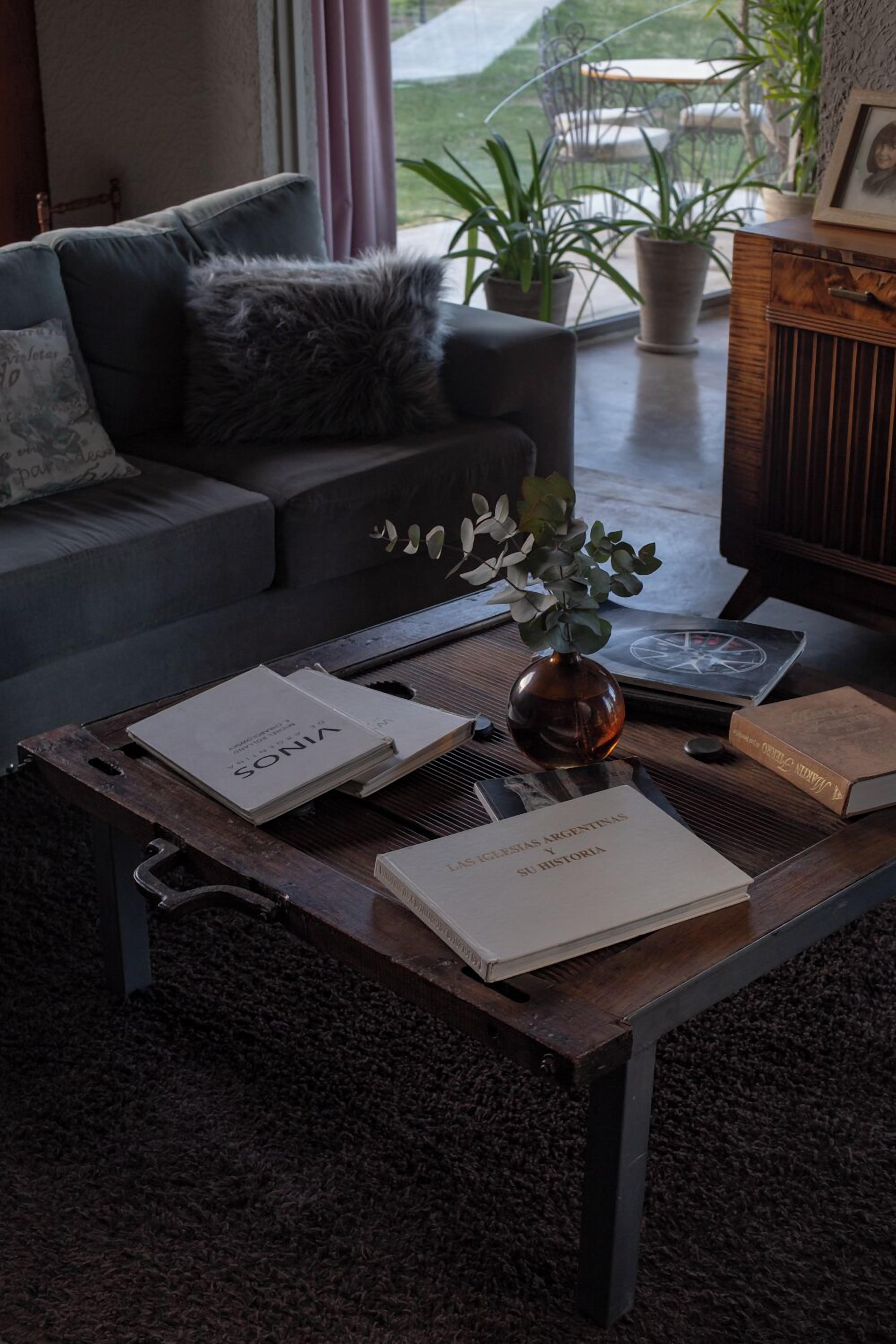 A living room with a sofa, a coffee table with books and a vase, and a view of the outdoors.
