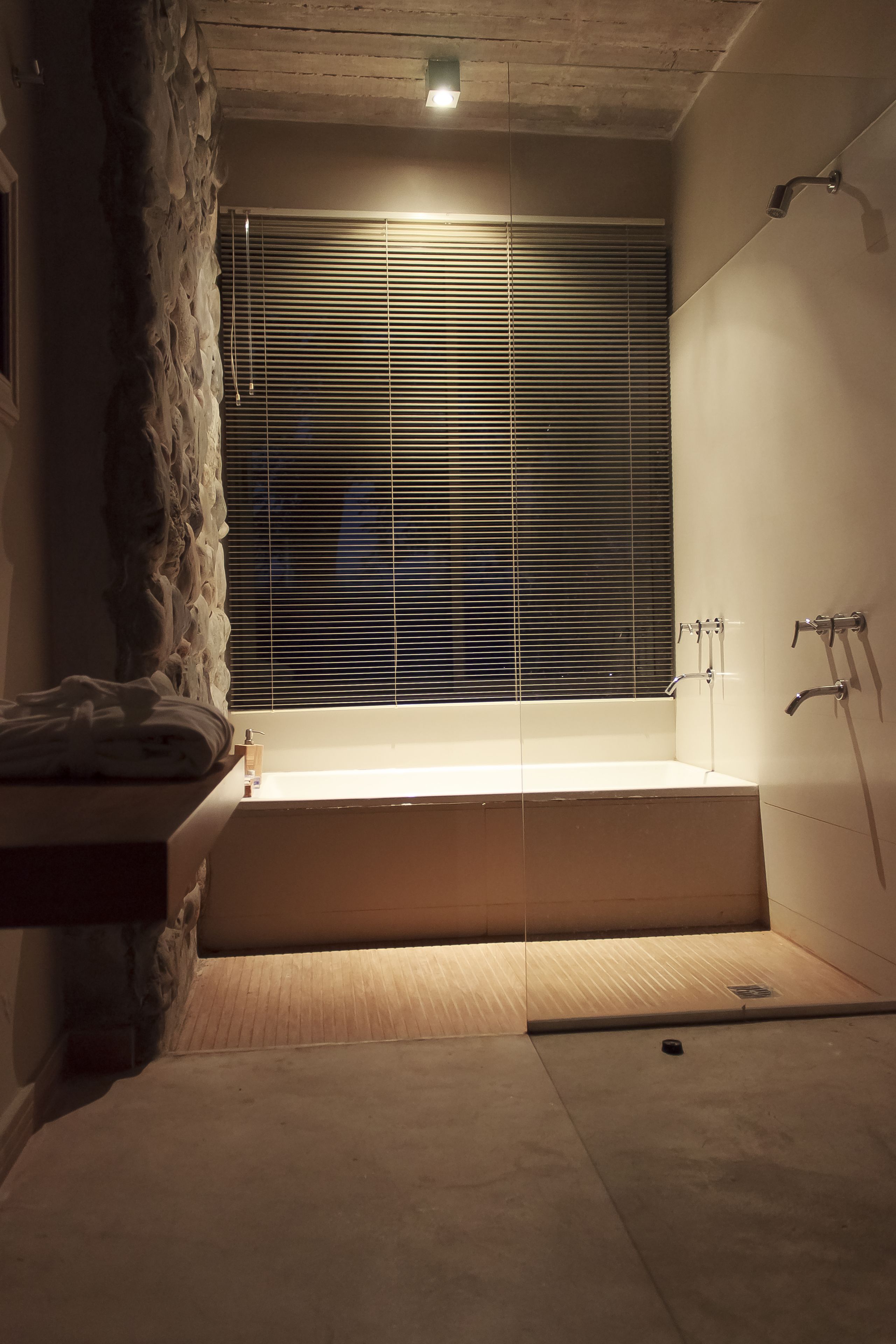 A modern bathroom with a bathtub, shower, and a stone accent wall.