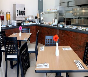 Ein Restaurant mit einer Marmor-Theke, schwarzen Stühlen und gedeckten Tischen.