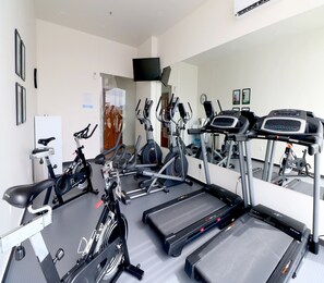 Ein Fitnessstudio mit verschiedenen Trainingsgeräten, darunter Laufbänder und Ergometer.