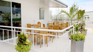 An outdoor patio with wooden tables and chairs, surrounded by potted plants. - Hotel Misión Express San Luis Potosí (San Luis Potosi)