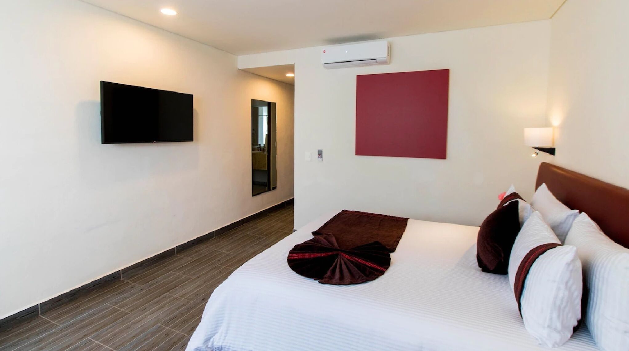 Een hotelkamer met een groot bed, een flatscreen televisie aan de muur en een rode accentmuur.