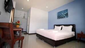 Una habitación de hotel moderna con una cama grande, un escritorio con silla, un televisor de pantalla plana en la pared y un cuadro.
