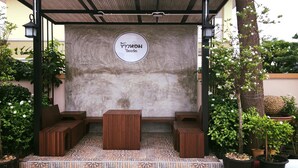 Una zona de estar al aire libre con techo, pared de piedra y un cartel.