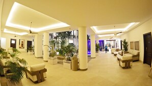 A spacious lobby with high ceilings, multiple seating areas, and potted plants. - Hotel Gran Balcón (Granada)