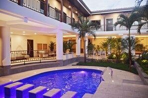 A pool area with a curved design, steps leading into the water, and a balcony overlooking the pool. - Hotel Gran Balcón (Granada)