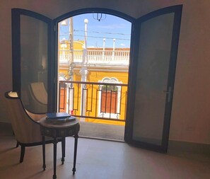 An open door leading to a balcony with a view of a yellow building and a white fence. - Hotel Gran Balcón (Granada)