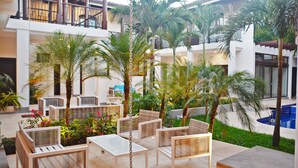 A spacious outdoor area with seating, palm trees, and a pool. - Hotel Gran Balcón (Granada)