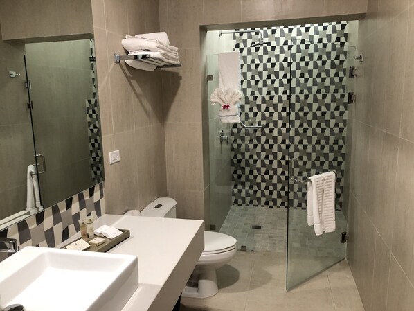A modern bathroom with a white sink, toilet, and glass shower enclosure. - Hotel Gran Balcón (Granada)