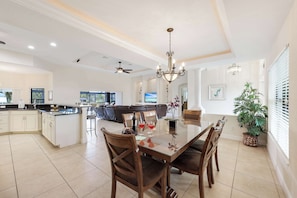 A spacious kitchen with a dining area, a ceiling fan, and a chandelier.