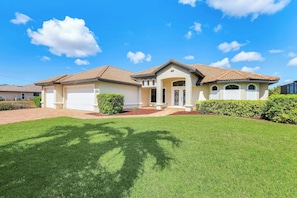 A two-story house with a front garage, a covered porch, and a well-maintained lawn.