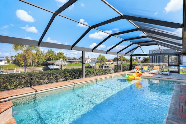 A swimming pool with a covered area, clear blue water, and a duck float.